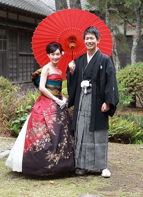 伝統的な黒紋付袴の新郎と黒と赤を基調とした着物ドレス姿の新婦